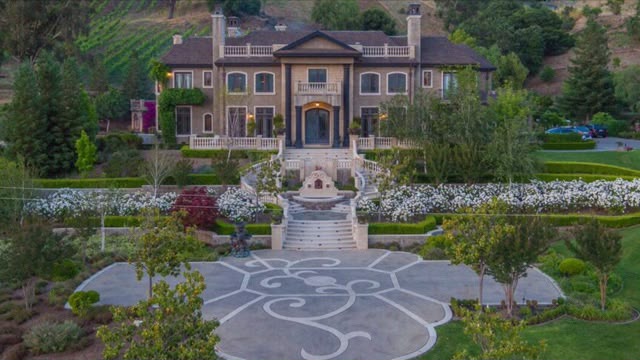 Aerial view of the Italianate villa at Castillo's Hillside Shire Winery, with terraced formal gardens, a fountain and stone staircases, flowering hedgerows, and the vineyard hillside behind
