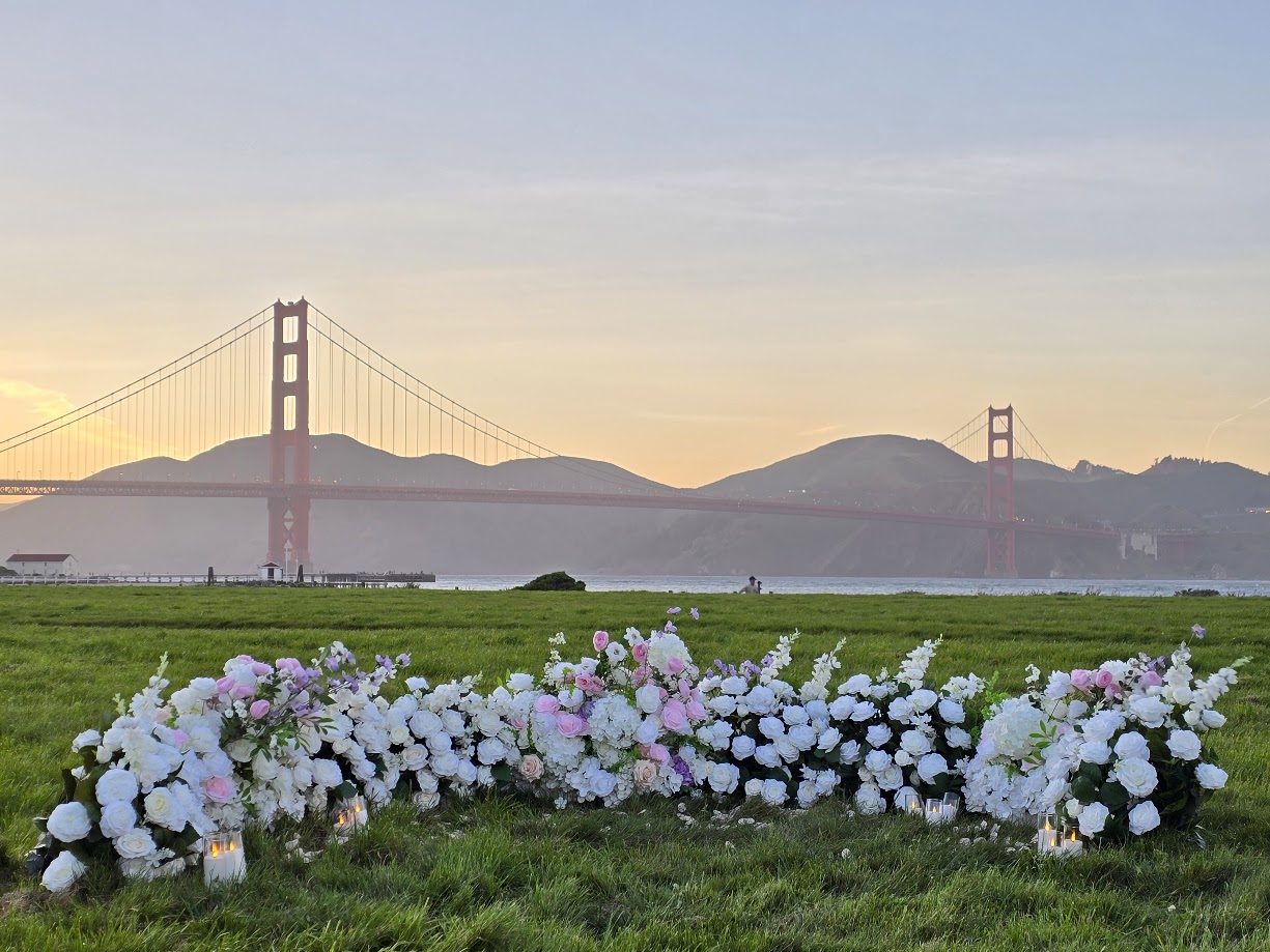Romantic grounded floral proposal setup at Crissy Field San Francisco with the Golden Gate Bridge visible across the bay